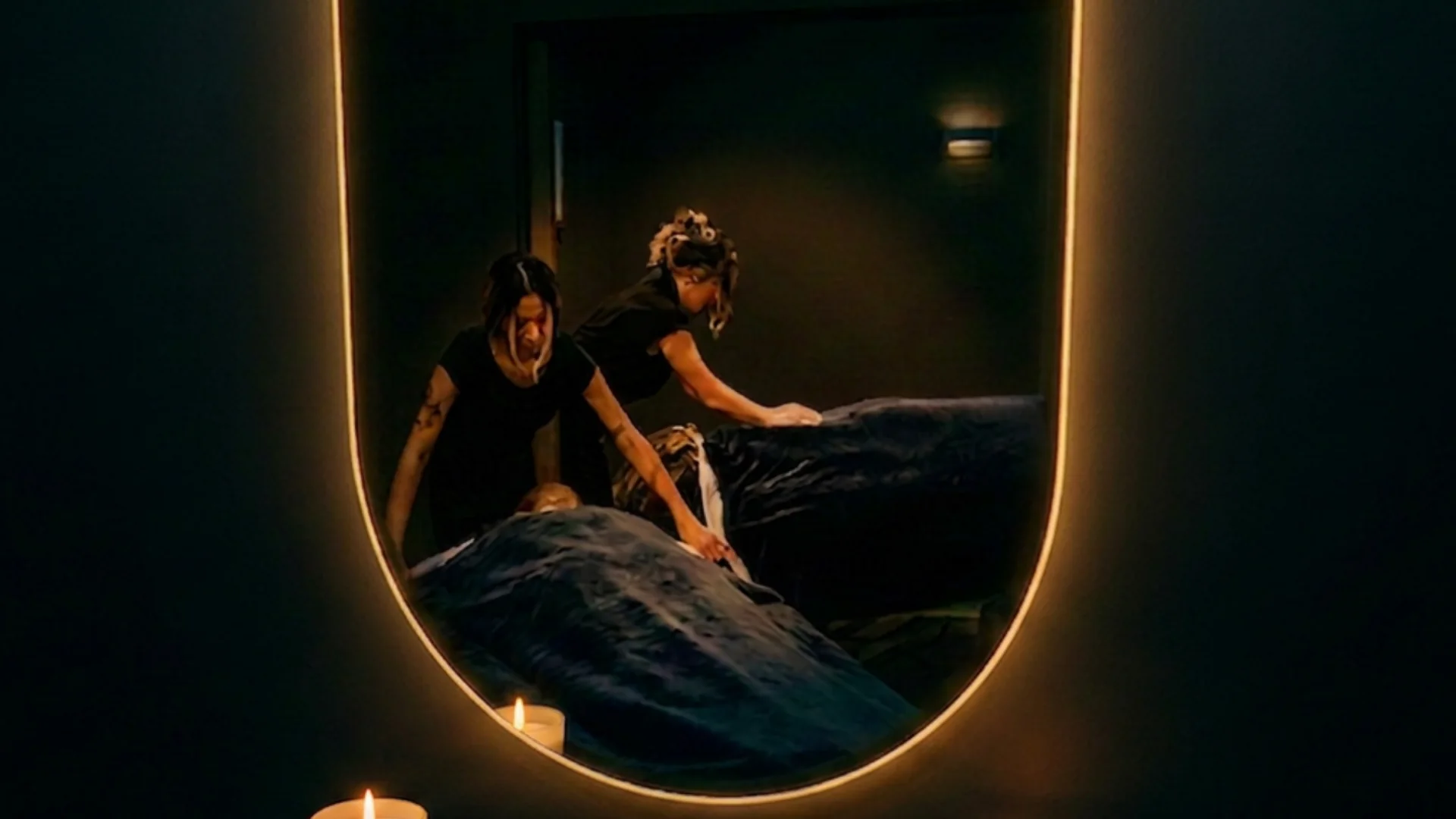 Mirror reflection of two massage therapists working side-by-side tables in the candlelit couples suite at Banyan and Bamboo, South Austin TX
